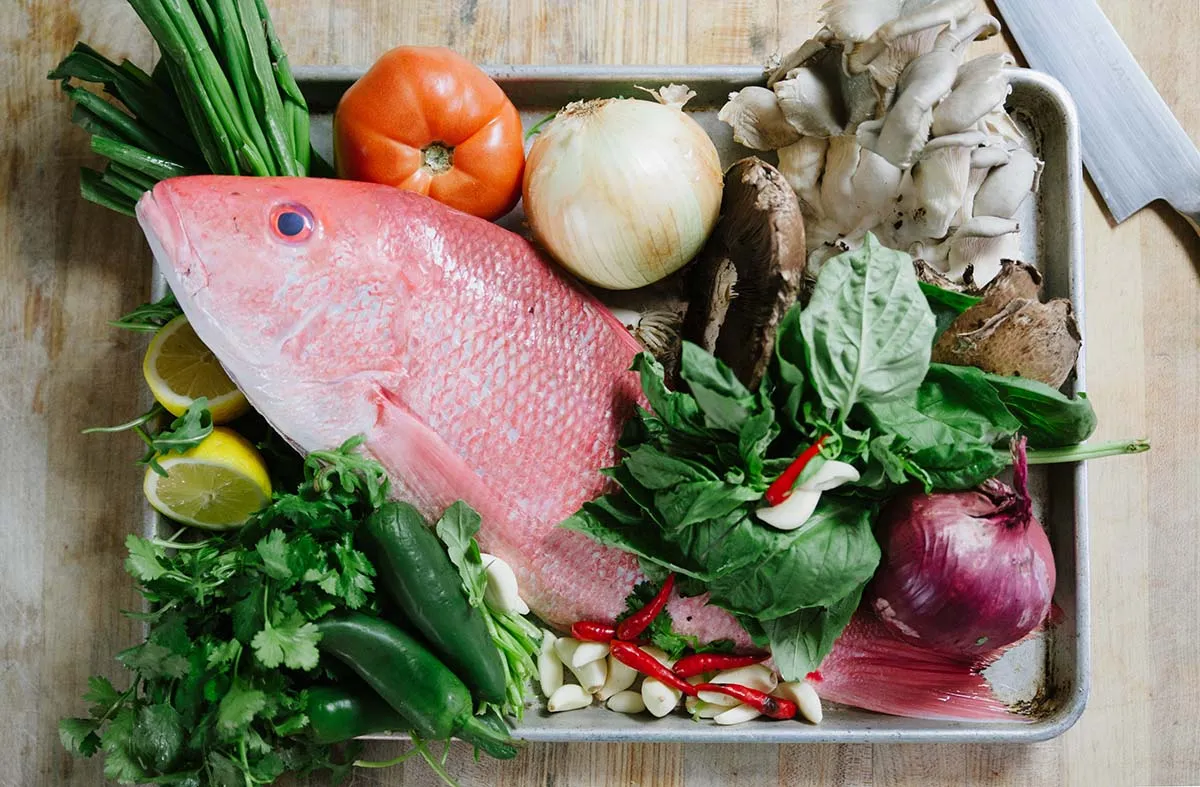 Fresh snapper with vegetables laid out on a tray