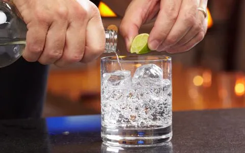 vodka being poured over ice with lime squeeze 1
